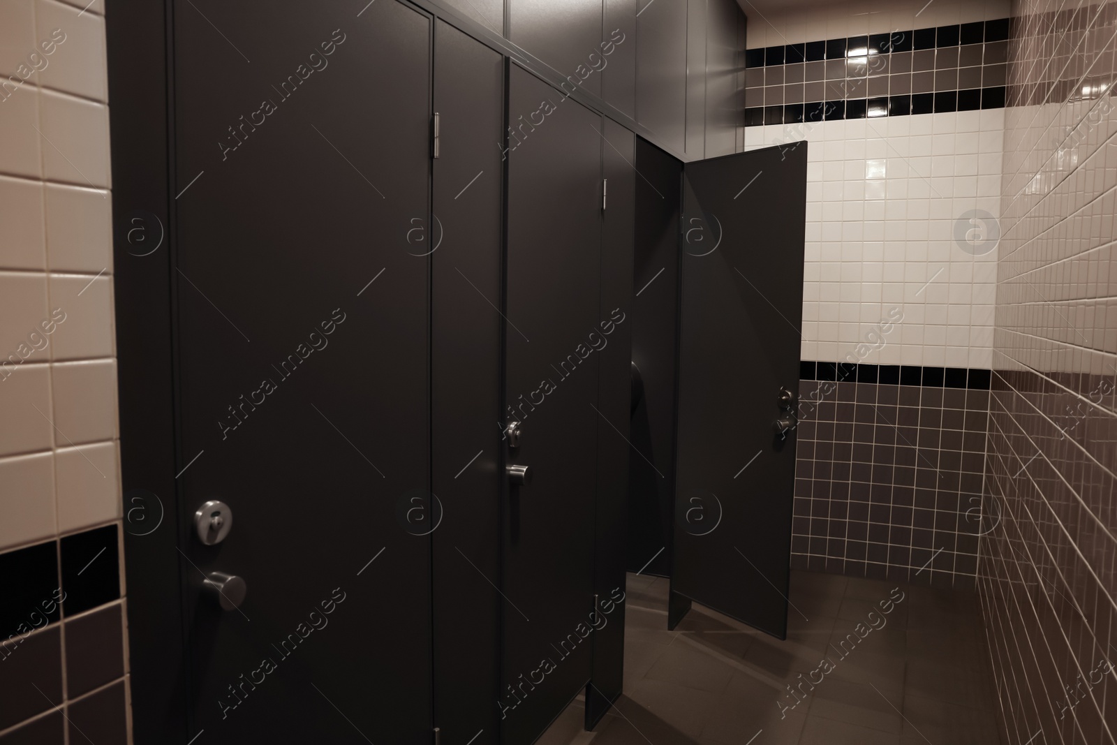 Photo of Public toilet interior with stalls and tiled walls