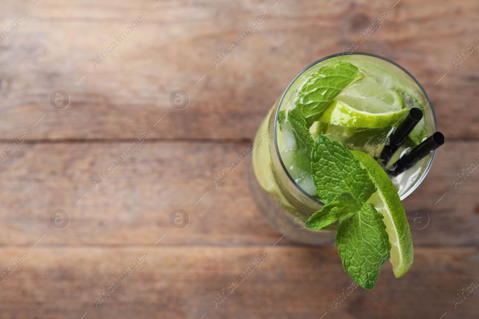Photo of Glass of tasty refreshing cocktail with lime and mint on wooden background, above view. Space for text