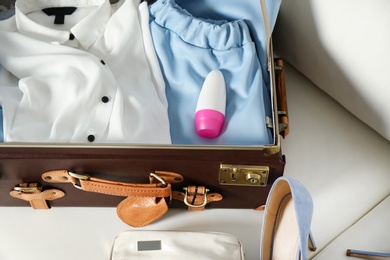 Vintage suitcase with deodorant and clothes indoors, closeup view