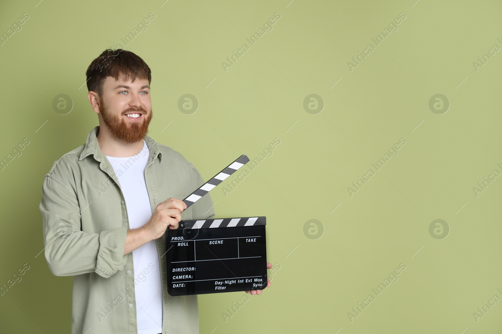 Photo of Making movie. Smiling man with clapperboard on green background. Space for text