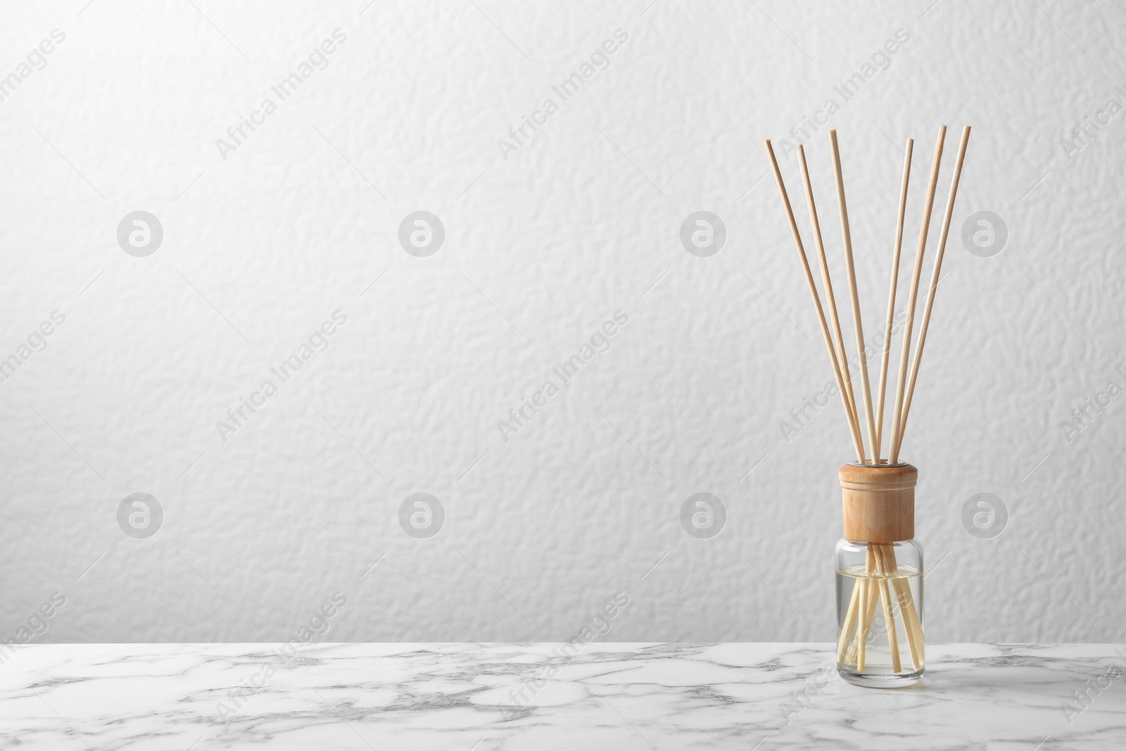 Photo of Aromatic reed freshener on marble table against light background, space for text