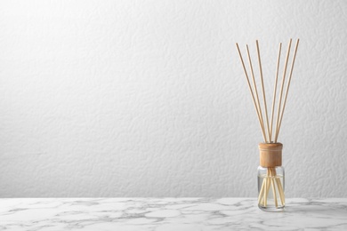 Aromatic reed freshener on marble table against light background, space for text