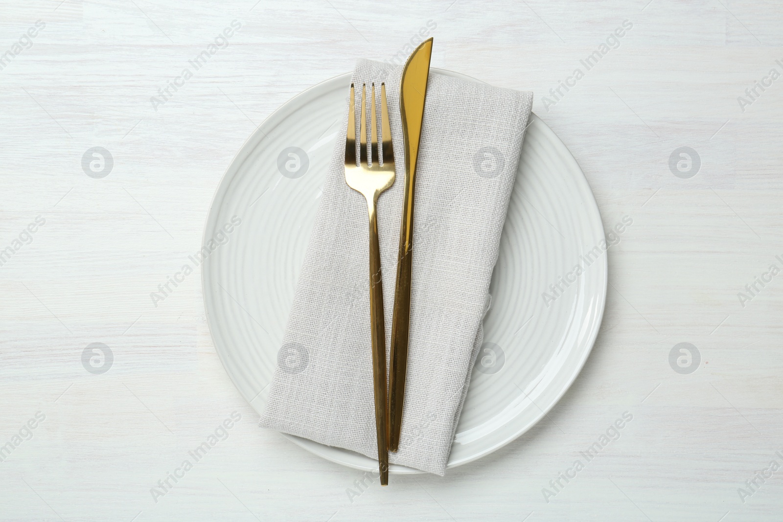 Photo of Stylish ceramic plate, cutlery and napkin on white wooden table, top view