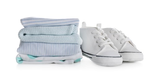 Photo of Stack of clean baby's clothes and small shoes on white background