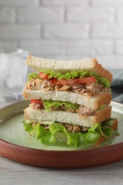 Photo of Delicious sandwich with tuna, tomatoes and lettuce on white wooden table, closeup