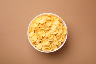 Photo of Breakfast cereal. Tasty corn flakes in bowl on brown table, top view