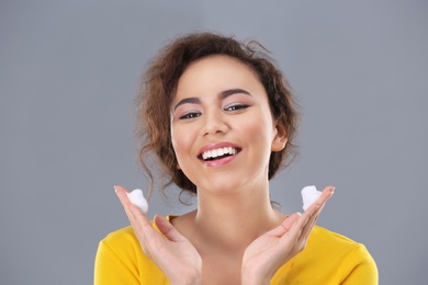 Photo of Beautiful young woman with problem skin applying anti acne cream on grey background