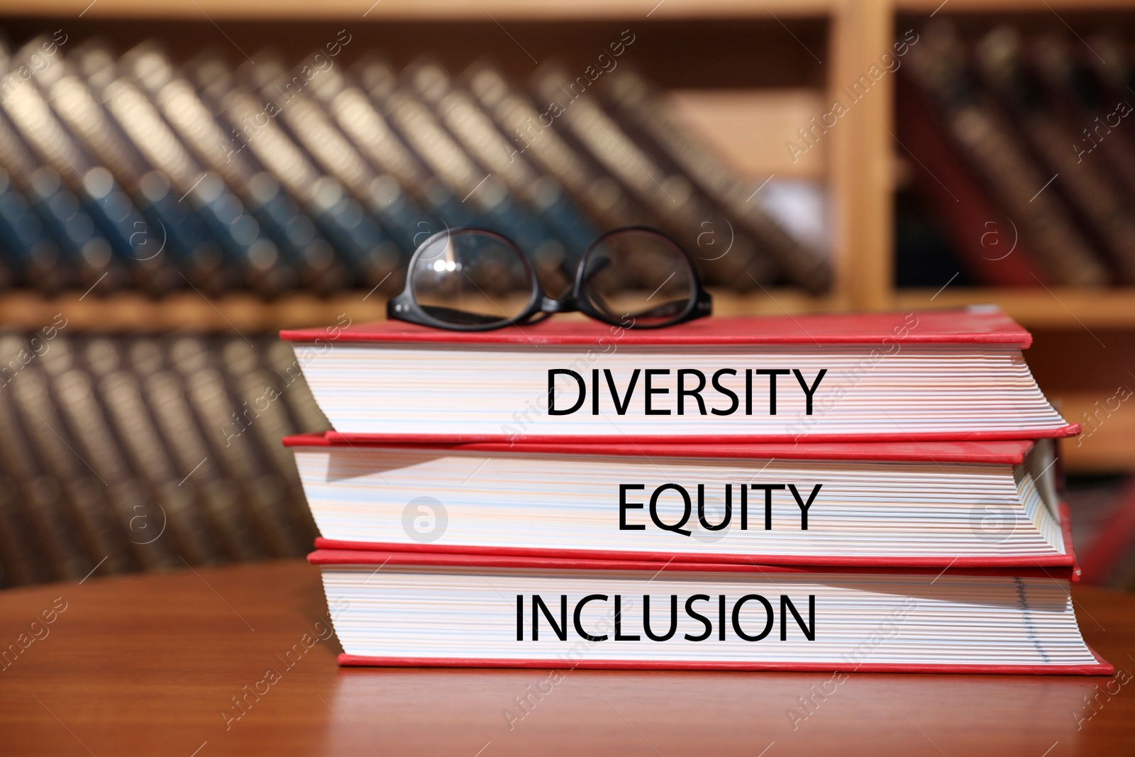 Image of Stack of books with words Diversity, Equity, Inclusion and glasses on table in library