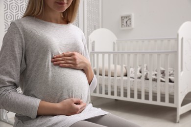 Photo of Pregnant woman in baby room, closeup view. Space for text