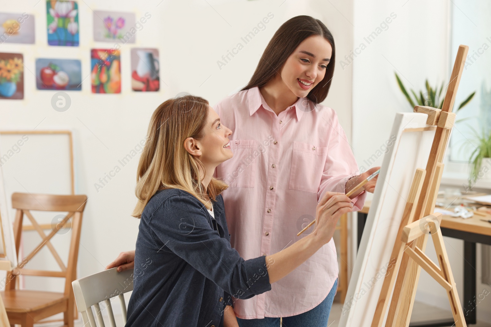 Photo of Artist teaching her student to paint in studio. Creative hobby