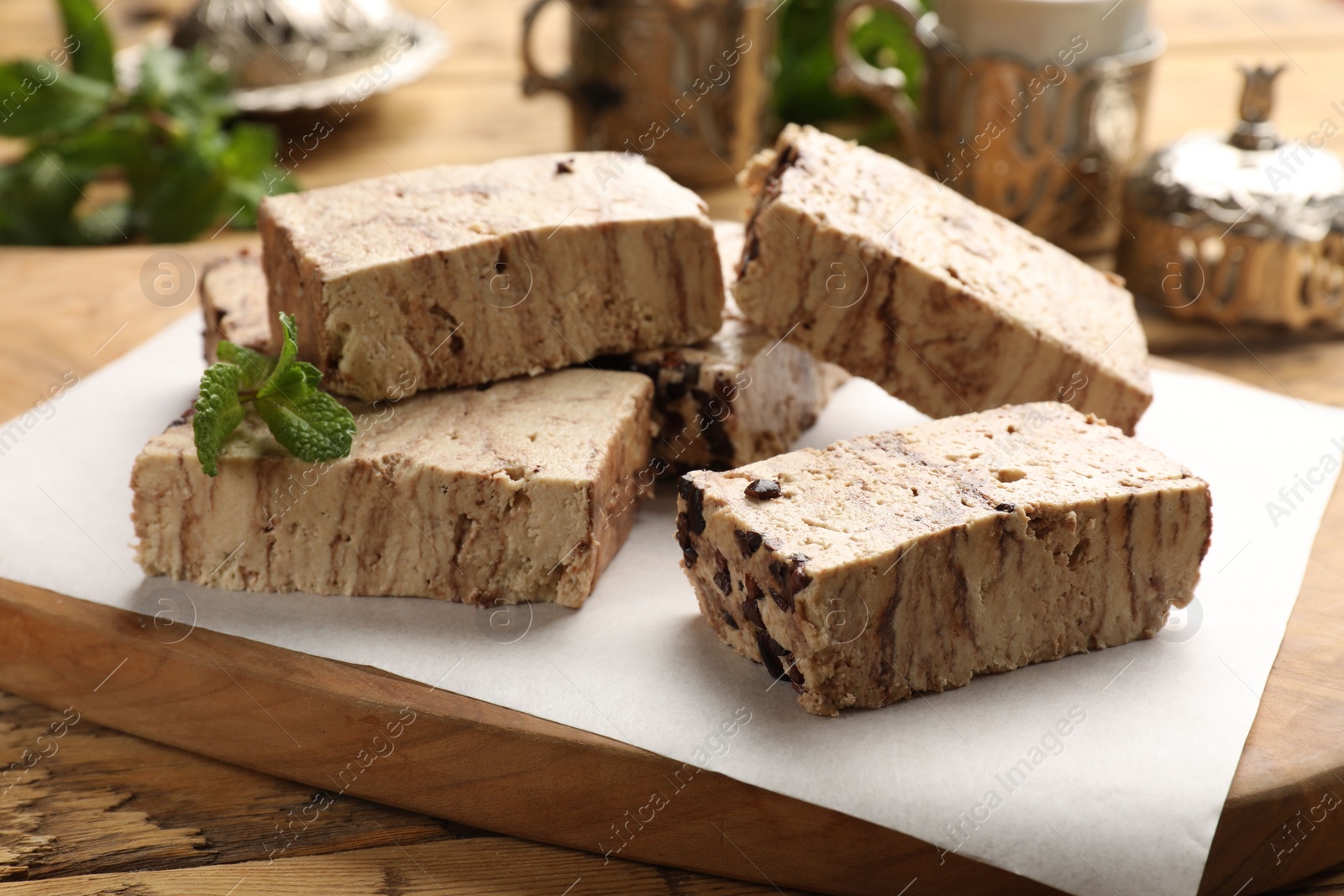 Photo of Tasty chocolate halva with mint on wooden table, closeup