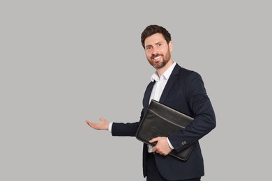 Happy real estate agent with leather portfolio on grey background. Space for text