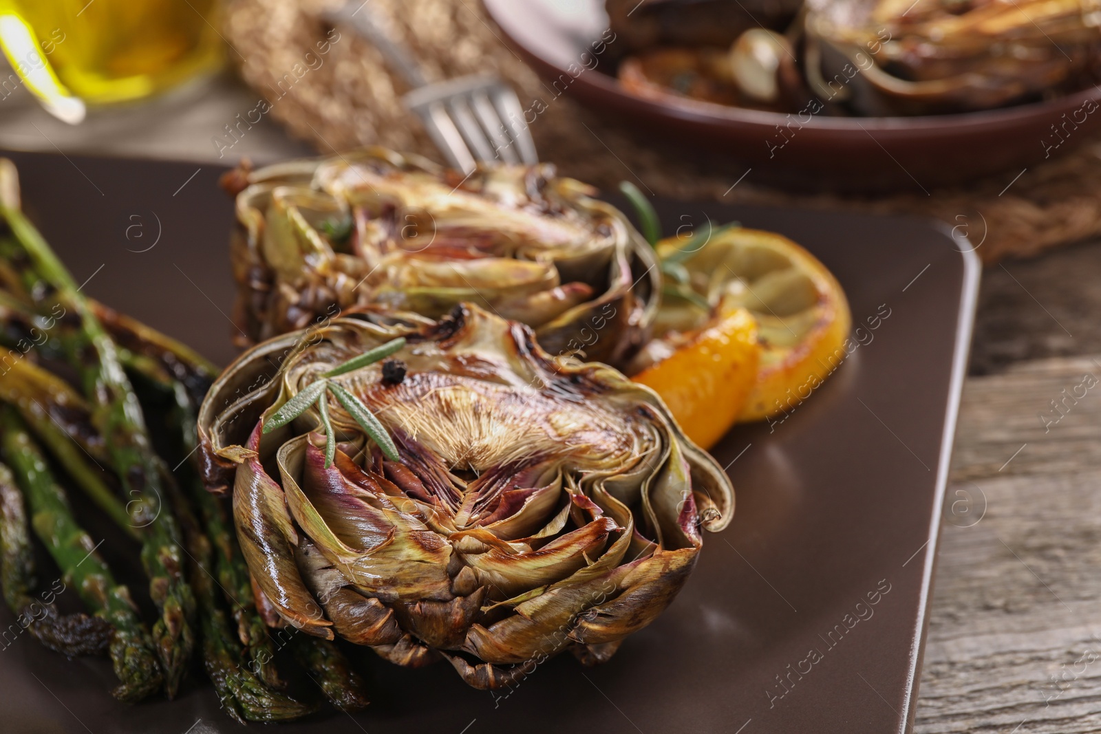 Photo of Tasty grilled artichoke served on table, closeup