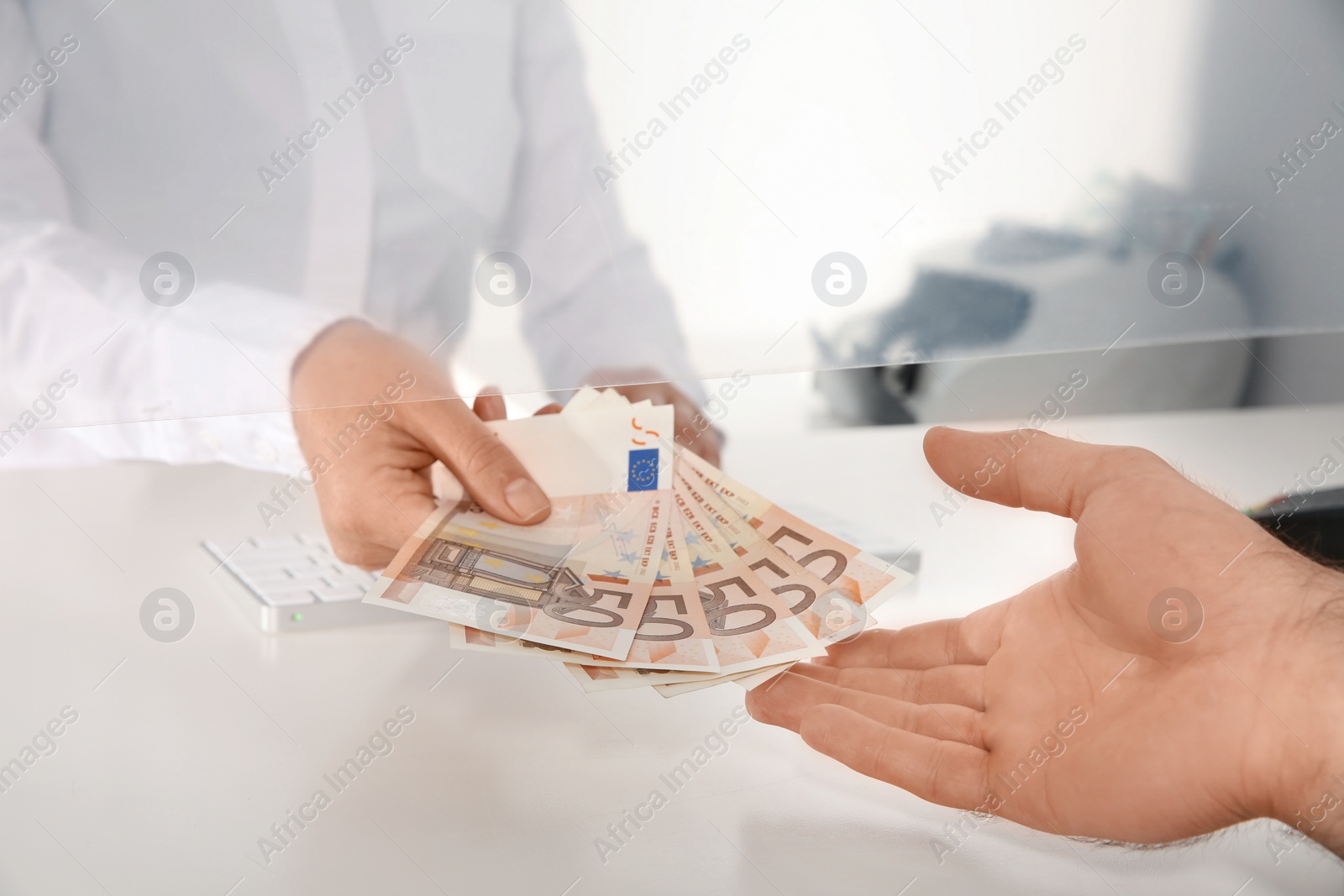 Photo of Man receiving money from teller at cash department window, closeup