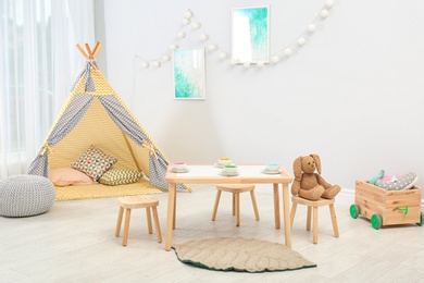 Cozy kids room interior with table, play tent and toys