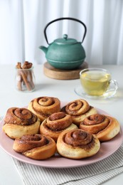 Photo of Many tasty cinnamon rolls on white table, closeup. Space for text
