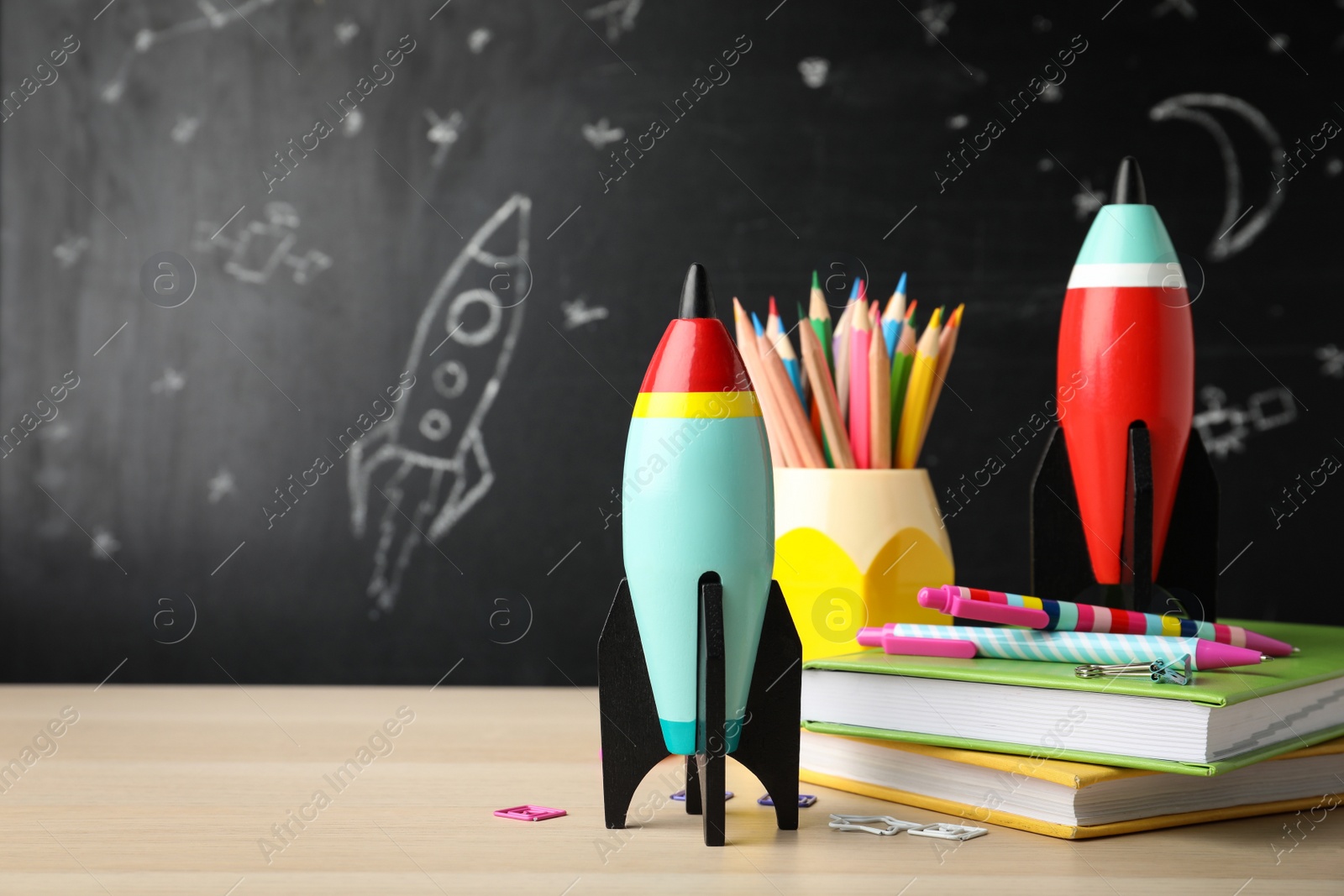 Photo of Bright toy rockets and school supplies on wooden table