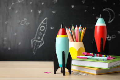 Bright toy rockets and school supplies on wooden table