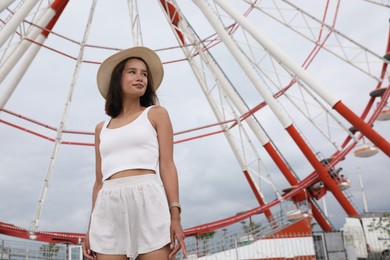 Beautiful young woman near Ferris wheel outdoors, low angle view