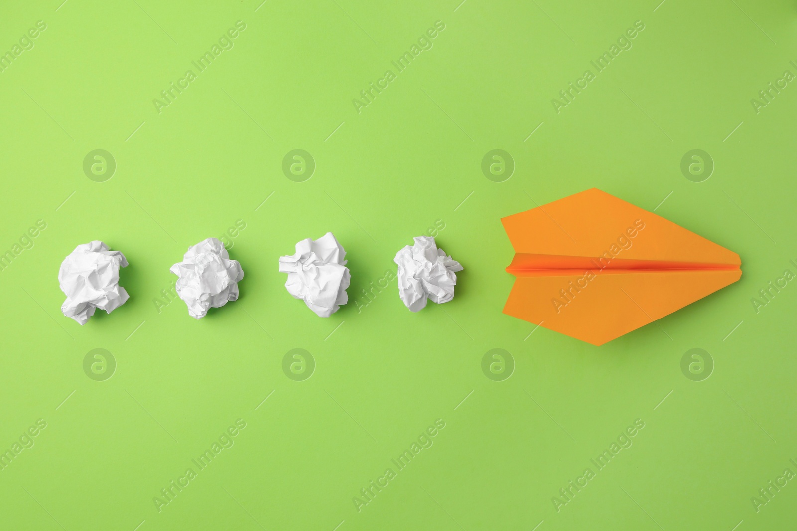 Photo of Idea concept. Handmade plane and many crumpled pieces of paper on green background, flat lay