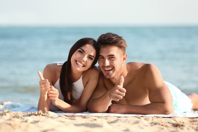 Photo of Happy young couple lying together on beach