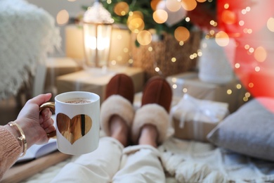 Photo of Woman with cup of cocoa in room decorated for Christmas, closeup