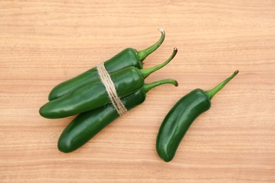 Fresh ripe green jalapeno peppers on wooden table, flat lay