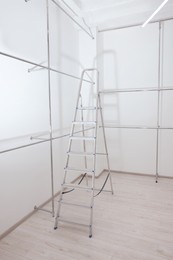 Photo of Ladder and metal pipes in empty renovated room