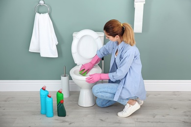 Photo of Woman cleaning toilet bowl in bathroom