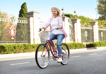 Photo of Mature woman riding bicycle outdoors. Active lifestyle