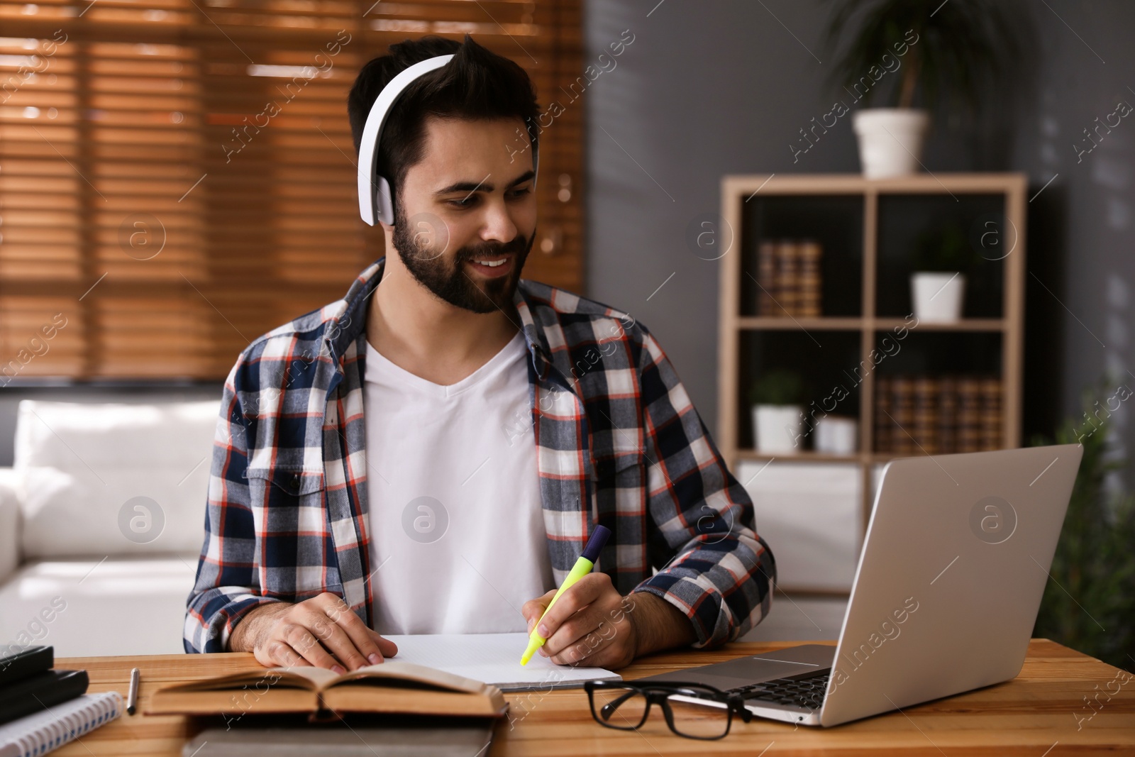 Photo of Young man watching webinar at table in room