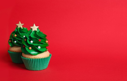 Photo of Christmas tree shaped cupcakes on red background. Space for text