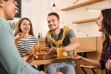 Photo of Group of friends having fun party with delicious pizza in cafe