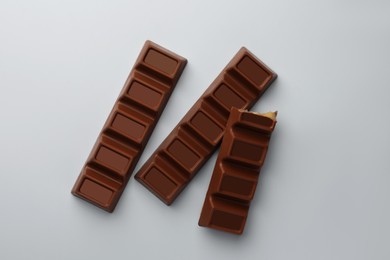 Delicious chocolate bars on light blue background, flat lay