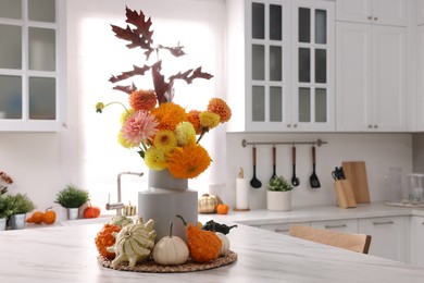 Beautiful autumn bouquet and pumpkins on marble table in kitchen