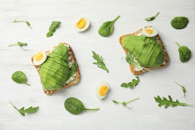 Photo of Flat lay composition with avocado toasts on white wooden table