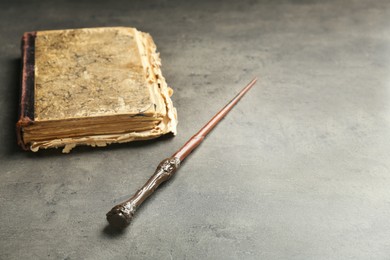 Photo of Magic wand and old book on light grey table, space for text