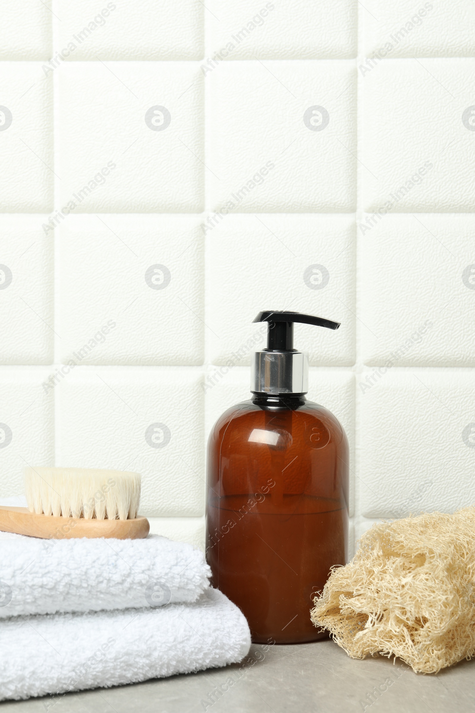 Photo of Different bath accessories and cosmetic bottle on gray table near white tiled wall