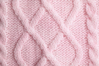 Pink knitted sweater as background, closeup view