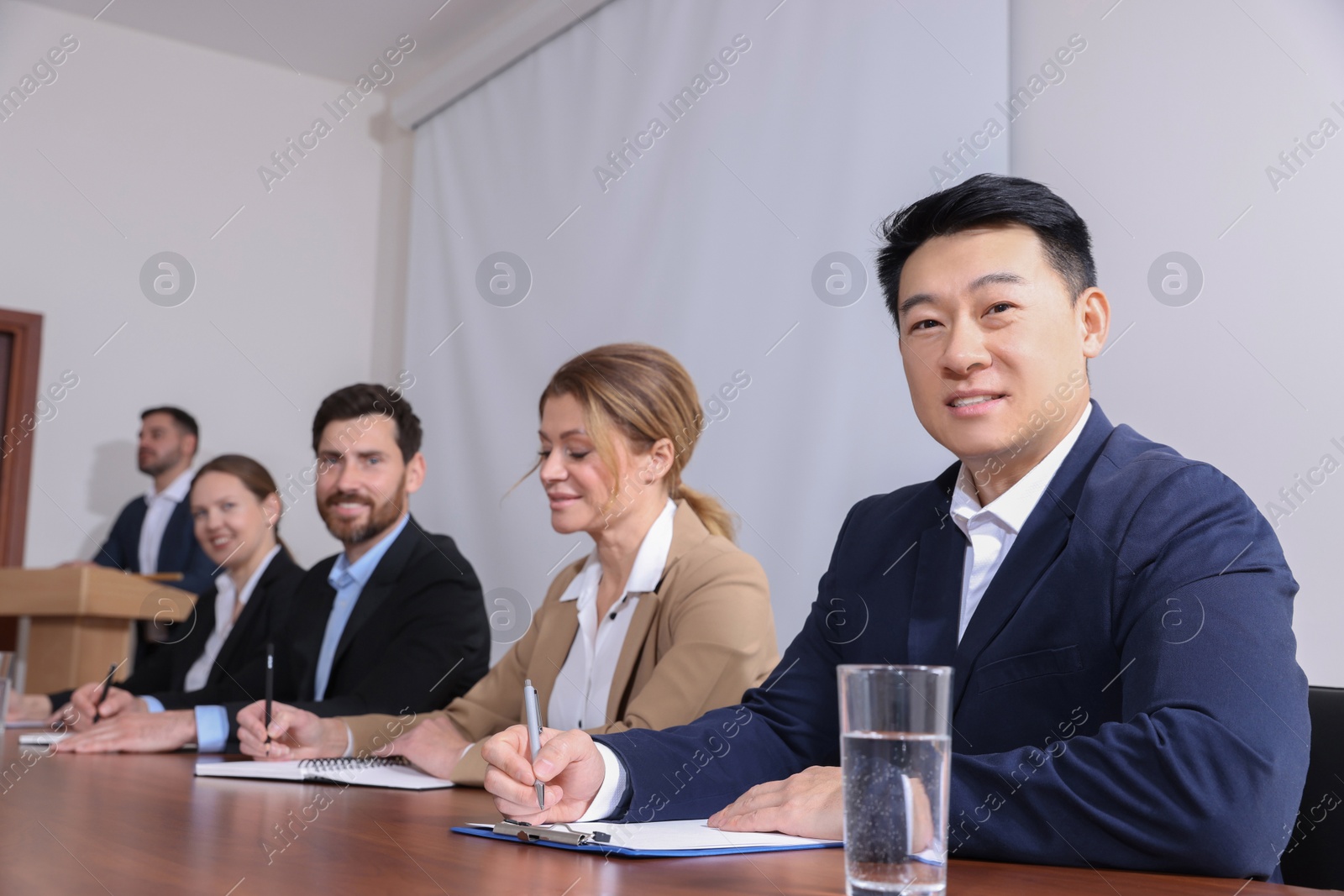 Photo of Business conference. People working at wooden table in meeting room