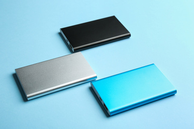 Photo of Modern external portable chargers on light blue background