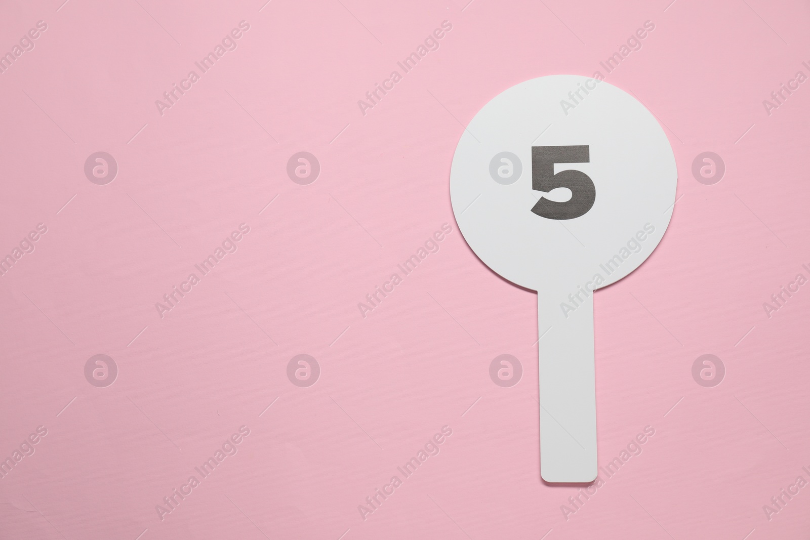 Photo of Auction paddle with number 5 on pink background, top view. Space for text