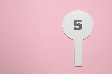 Auction paddle with number 5 on pink background, top view. Space for text