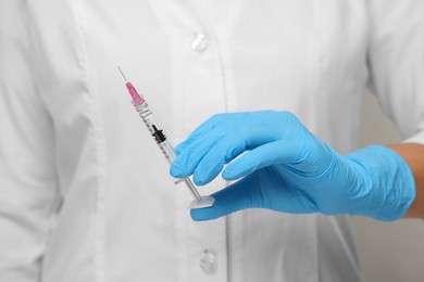 Doctor holding syringe with needle, closeup view