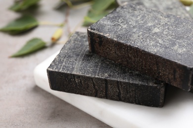 Photo of Natural tar soap on light grey stone table, closeup