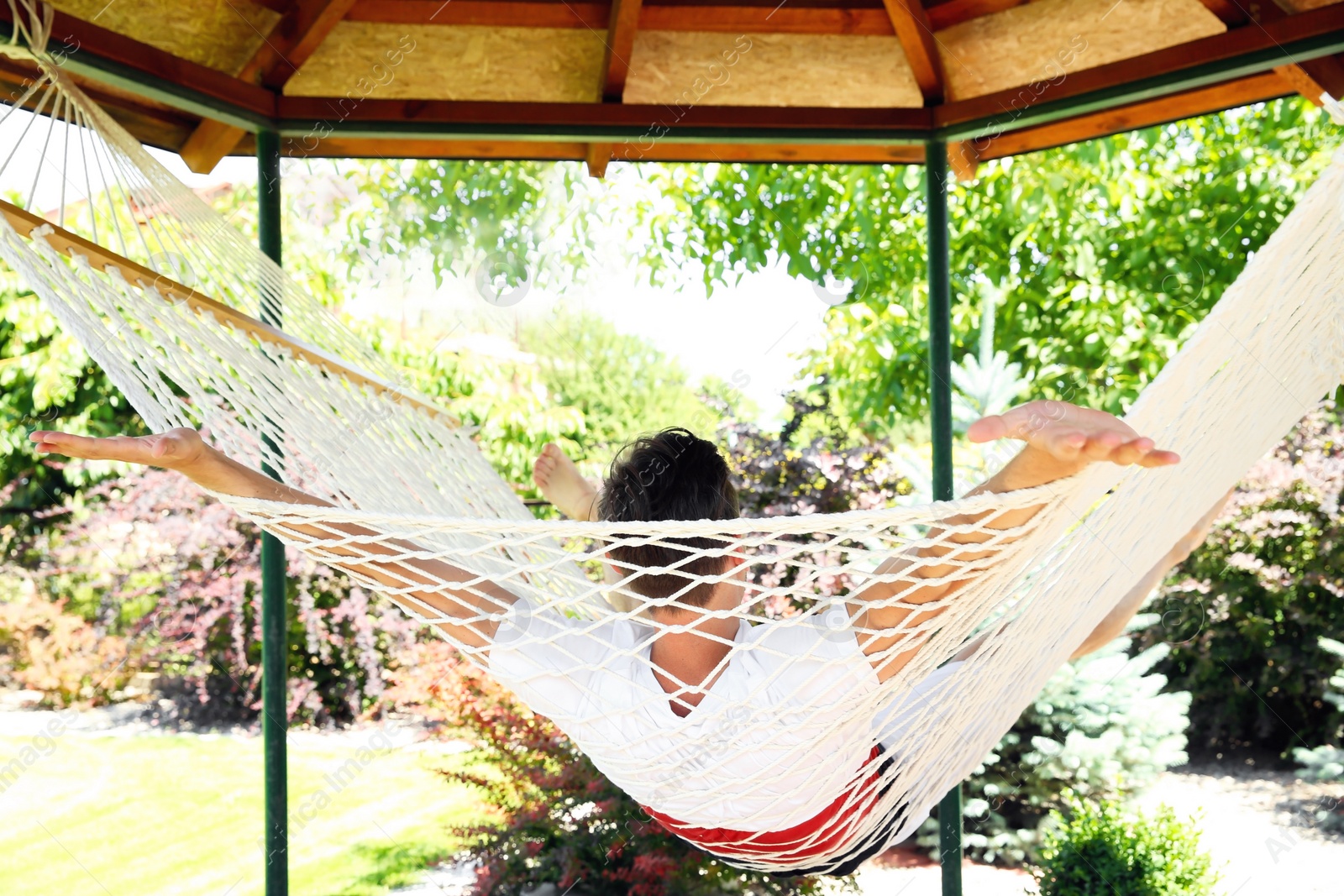 Photo of Man relaxing in hammock outdoors on warm summer day