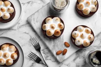 Photo of Delicious salted caramel chocolate tarts with meringue and coffee on white marble table, flat lay