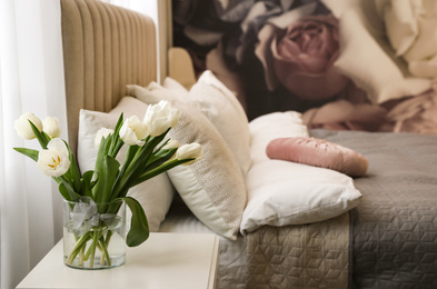 Vase with white tulips on table in bedroom. Interior element