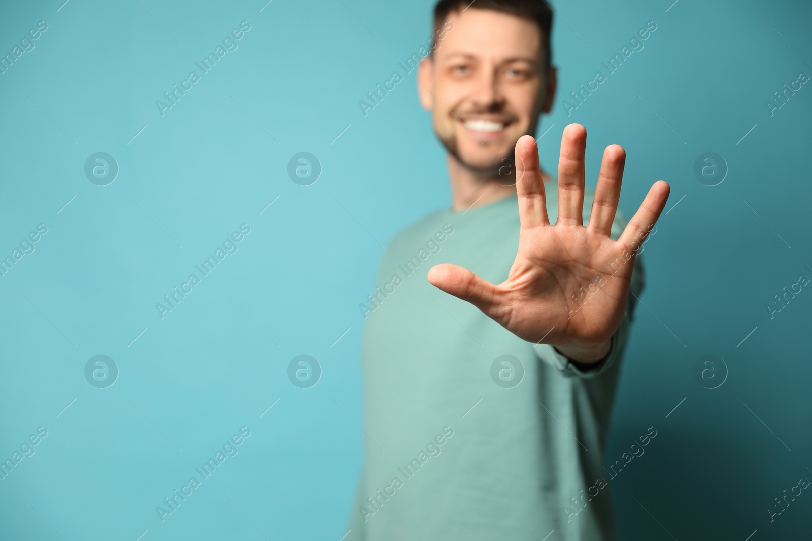 Photo of Left-handed man against light blue background, focus on palm. Space for text