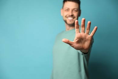 Photo of Left-handed man against light blue background, focus on palm. Space for text
